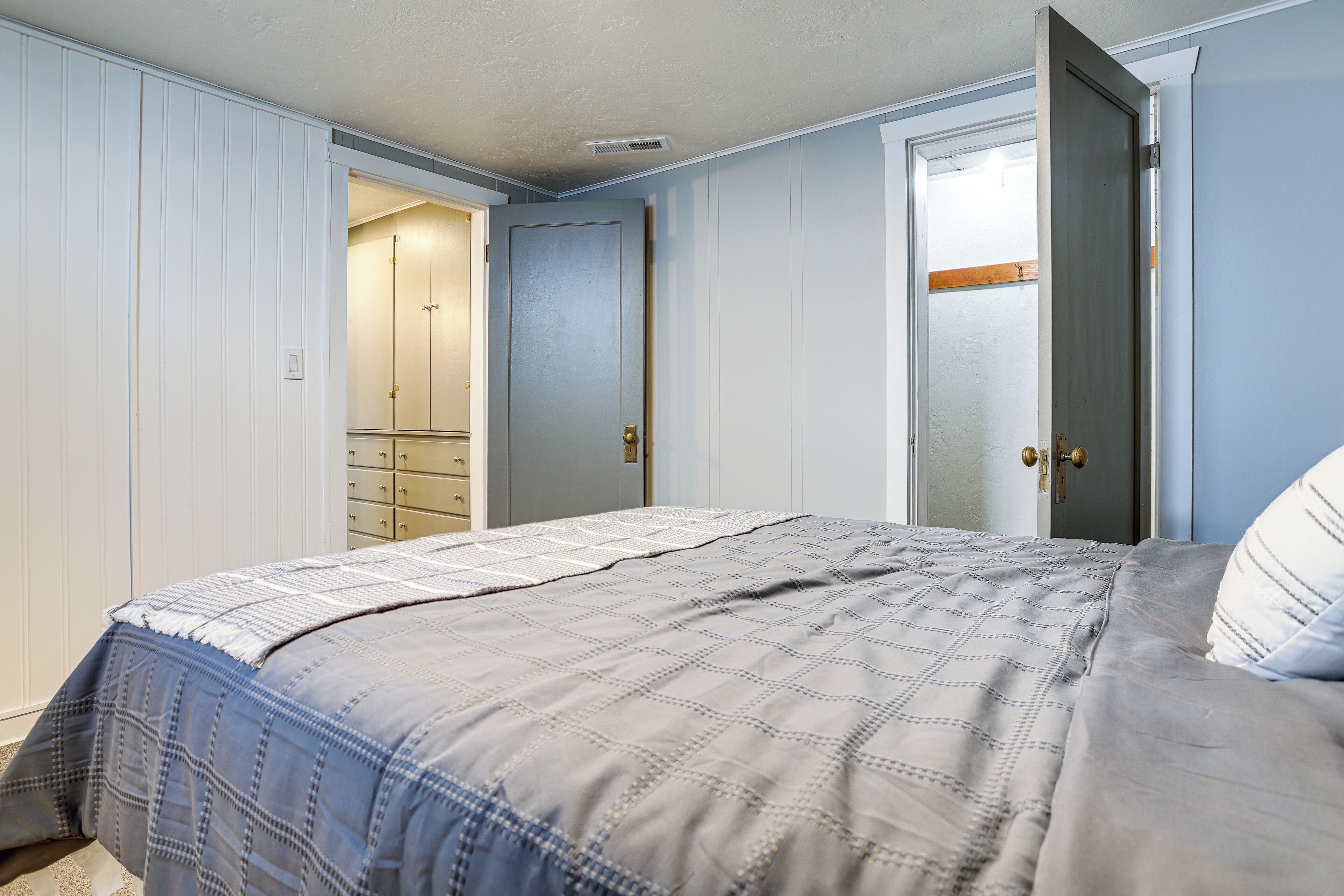 Un dormitorio con cama, armario y puerta que da a otra habitación.