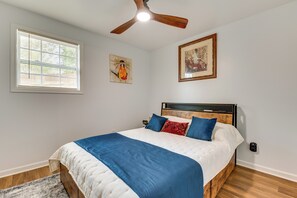 Ein Schlafzimmer mit Bett, Deckenventilator, Kunstwerken und einem Fenster.