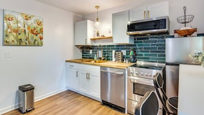 A modern kitchen with white cabinets, a stainless steel dishwasher, a microwave, and a stove. - Couple’s Retreat! 7 Mi to Dtwn Atlanta & Six Flags (Atlanta)