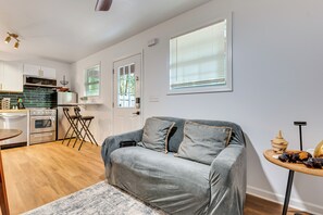 Eine moderne Küche mit Edelstahlgeräten, ein graues Sofa mit Kissen und ein kleiner runder Tisch mit Dekoration.