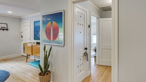 Een gang met houten vloer, een blauw vloerkleed, een plant en een deur met een deurklink.