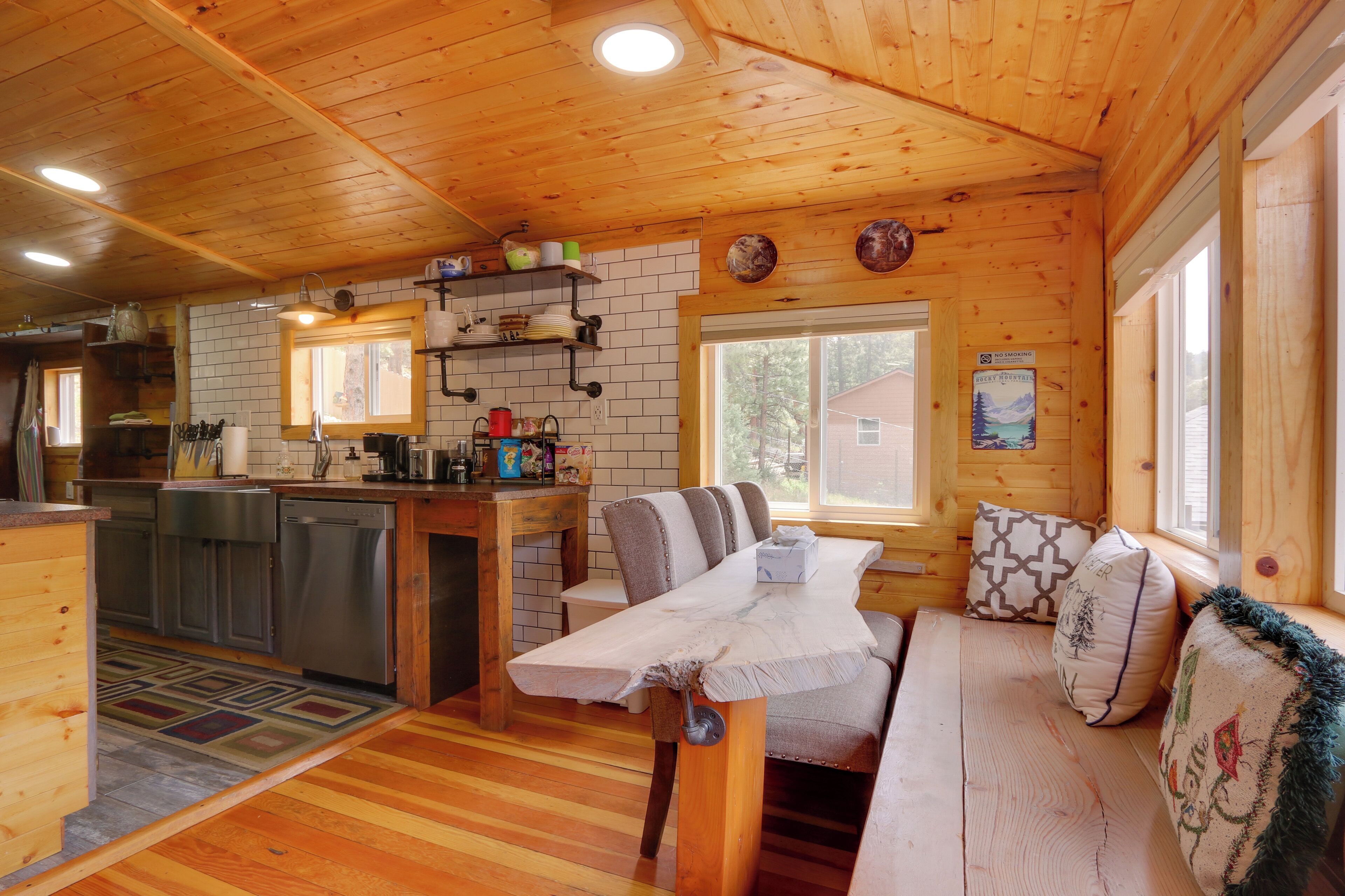 A cozy cabin interior with a wooden interior, a dining area with a bench, and a kitchen with a dishwasher.