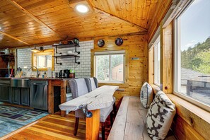 Ein Holzblockhaus-Interieur mit Küche, Essbereich und großen Fenstern.