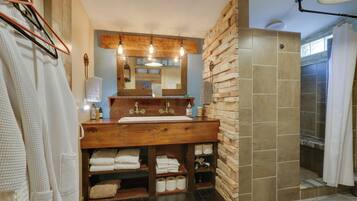 A bathroom with a wooden vanity, a large mirror, and a shower area.