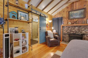 A cozy cabin interior with a stone fireplace, a leather armchair, and a wooden floor. - Fish & Hike! Hot Tub Haven 2 Mi to Estes Park (Drake)