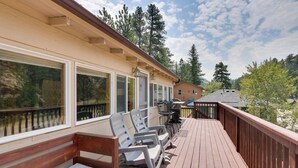 Une terrasse en bois avec des sièges extérieurs et une vue sur une zone boisée.
