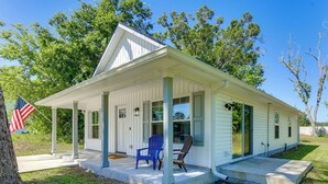 Een gelijkvloers huis met een veranda, een vlag en twee stoelen.