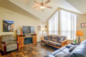 A living room with a fireplace, a television, a sofa, and a ceiling fan. - 'Fox Cabin' - 6 Blocks to Yellowstone Nat'l Park! (West Yellowstone)