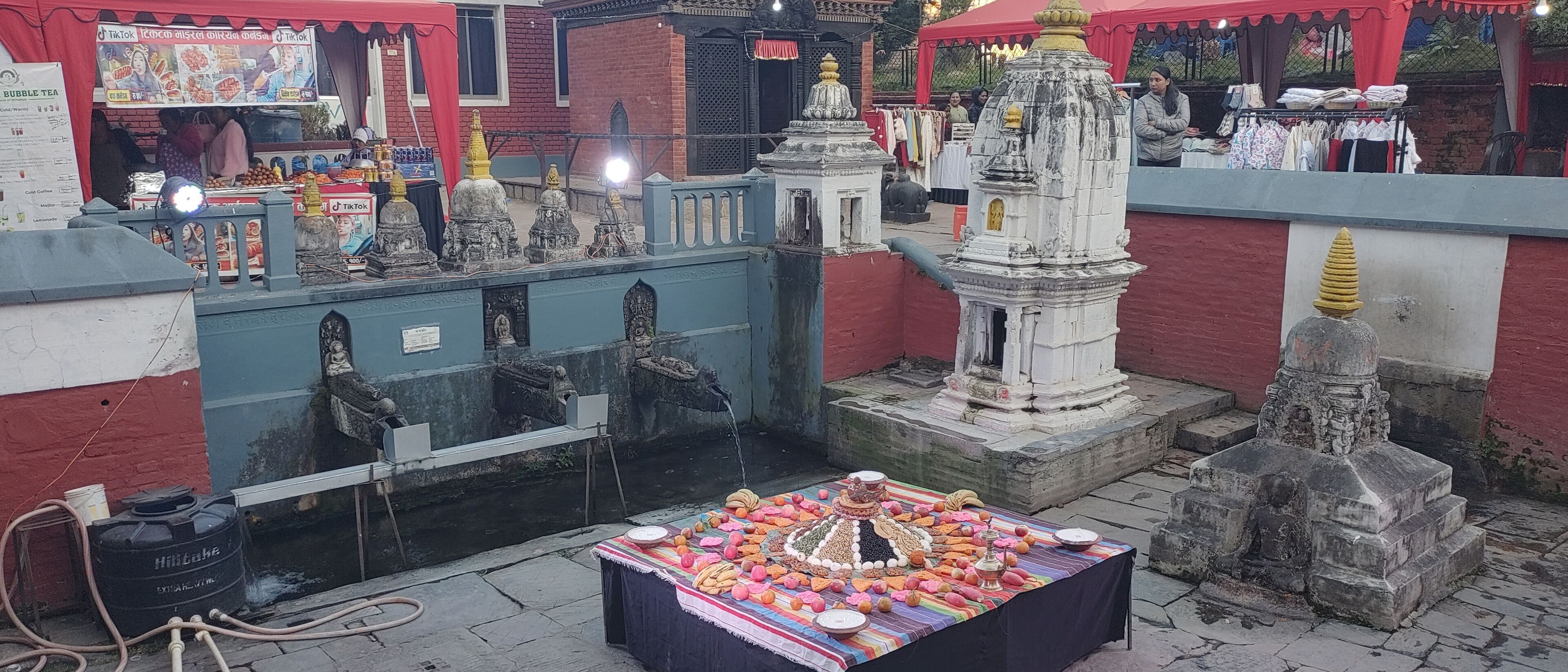 A temple with a water body, a small shrine, and a table with offerings.