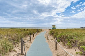 A pathway leading to a beach with a lifeguard tower, surrounded by sand and vegetation. - Elegant Waterfront Condo w/ Views in Pompano Beach (Pompano Beach)