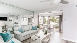 Una sala de estar moderna con un sofá gris, una mesa de centro blanca y un comedor con mesa y sillas.