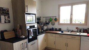 A kitchen with a double oven, a sink, and a window.