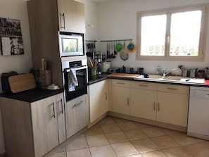 A kitchen with a double oven, a sink, and a window.