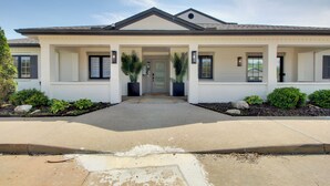Une maison à deux étages avec un porche à l’avant, un garage et un jardin paysager.