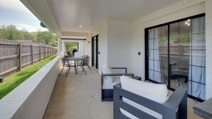 Un patio couvert avec une table et des chaises, un coin salon confortable et une vue sur le jardin arrière.