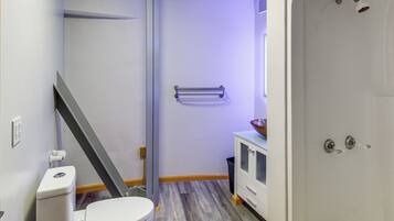 A bathroom with a toilet, a shower, a sink, and a towel rack.