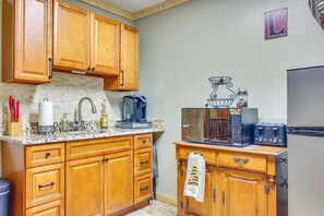 Una cocina con armarios de madera, un microondas, una cafetera y un tostador.