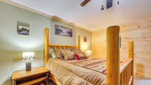 Um quarto com cama de madeira, mesas de cabeceira, luminária e uma pequena mesa.