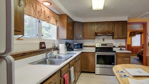 A kitchen with wooden cabinets, a microwave, a stove, and a sink. - Gateway to Yellowstone! Cabin < 1 Mi to Nat'l Park (West Yellowstone)