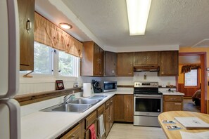 A kitchen with wooden cabinets, a microwave, an oven, and a sink. - Gateway to Yellowstone! Cabin < 1 Mi to Nat'l Park (West Yellowstone)