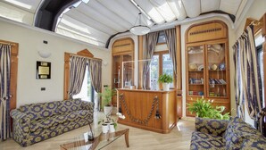 A spacious living area with a sofa, a glass coffee table, and a wooden reception desk. - Golf View Apartment for Two (Roma)