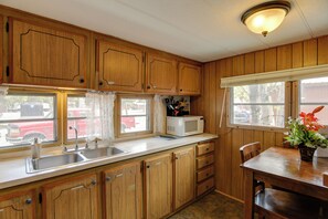A kitchen with wooden cabinets, a sink, a microwave, and a dining table with chairs. - 6 Blocks to Yellowstone NP: 'Bison Home' w/ BBQ (West Yellowstone)