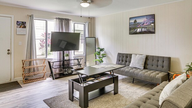 Una sala de estar con sofá, mesa de centro, televisor y estantería.