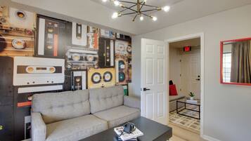 A living room with a sofa, a coffee table, and a wall decorated with cassette tapes.
