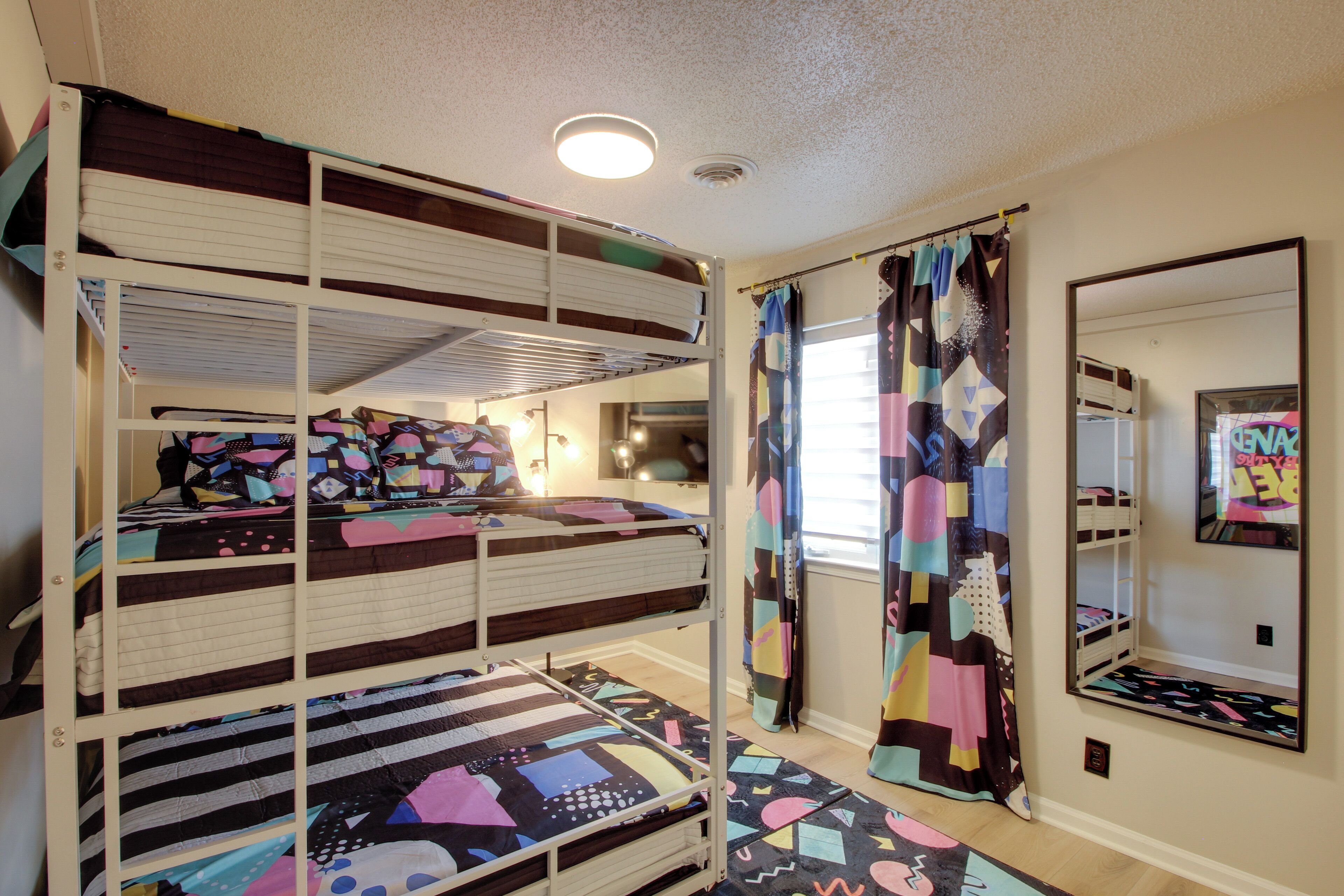 A bunk bed room with a mirror and a colorful curtain.