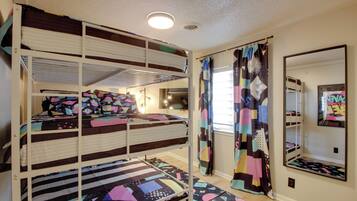 A bunk bed room with a mirror and a colorful curtain.