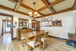 Ein Essbereich mit Holztisch und Stühlen, einer Kristallleuchtre und gerahmten Bildern an der Wand.