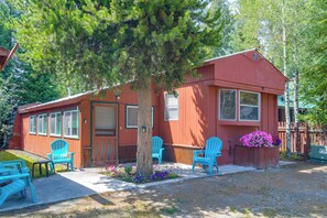 A red cabin with a porch, two blue chairs, and a flower planter. - 'Elk Home' - Yellowstone Basecamp < 1 Mi to Park! (West Yellowstone)