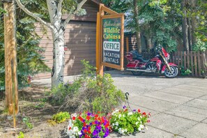 A wooden signboard for Yellowstone Wildlife Cabins Office with a motorcycle parked nearby. - 'Elk Home' - Yellowstone Basecamp < 1 Mi to Park! (West Yellowstone)