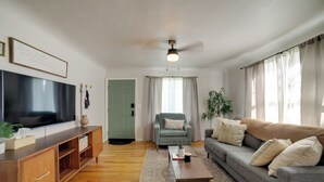 Ein Wohnzimmer mit Flachbildfernseher, Holz-Multimediamöbel, grauem Sofa und Couchtisch.