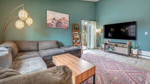 Ein Wohnzimmer mit einem Ecksofa, einem Couchtisch, einem Fernseher und einem gemusterten Teppich.