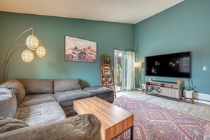 Ein Wohnzimmer mit einem Ecksofa, einem Couchtisch, einem Fernseher und einem gemusterten Teppich.