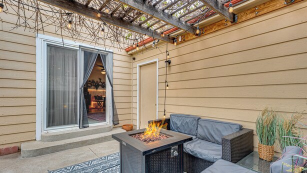 Eine Terrasse im Freien mit Feuerstelle, Sitzgelegenheiten und einem überdachten Bereich mit Lichterketten.
