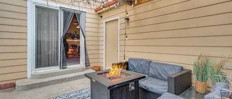 An outdoor patio with a fire pit, seating, and a covered area with string lights.