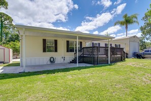 A single-story mobile home with a covered porch, a small front yard, and a vehicle parked nearby. - Near Rocket Launches & Beaches! Cocoa Family Home (Cocoa)