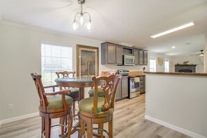 A kitchen with a dining area, wooden chairs, a glass table, and a ceiling light fixture. - Near Rocket Launches & Beaches! Cocoa Family Home (Cocoa)