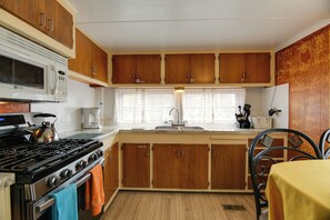 A kitchen with wooden cabinets, a stove, a microwave, and a sink. - 'Wolf Home' - Walk to Yellowstone Nat'l Park (West Yellowstone)