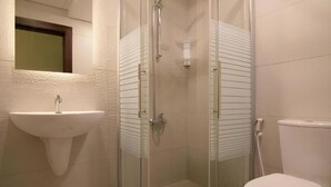Un baño con ducha de vidrio, un lavabo blanco y un inodoro.