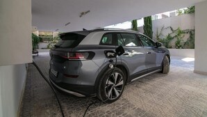Un SUV gris estacionado en un área de estacionamiento techada con piso de baldosas y pared blanca.