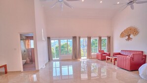 A spacious living area with a large window, a ceiling fan, and a red sofa. - Ice Cliff Munnar by VOYE HOMES (Munnar)