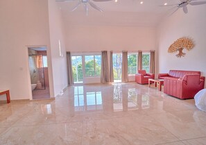 A spacious living area with a large window, a ceiling fan, and a red sofa. - Ice Cliff Munnar by VOYE HOMES (Munnar)