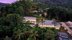 A resort with multiple buildings surrounded by dense tropical vegetation and hills. - Ice Cliff Munnar by VOYE HOMES (Munnar)