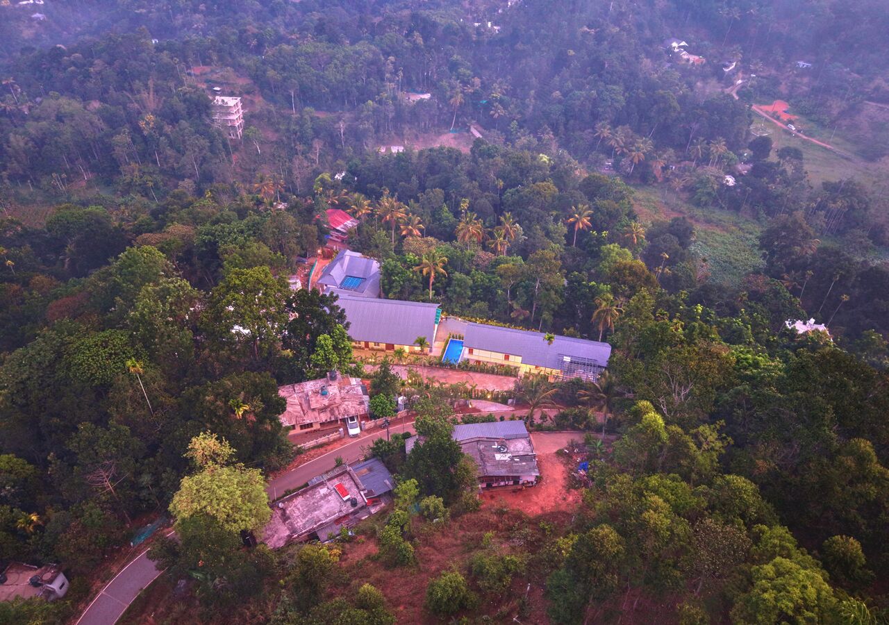 Vista aérea de una propiedad con varios edificios, rodeada de un bosque denso.