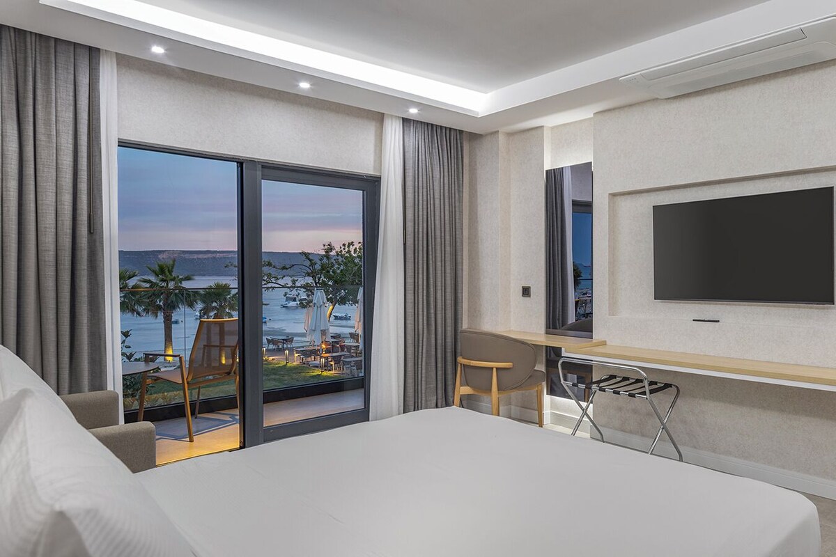 Ein Hotelzimmer mit Bett, Schreibtisch, Fernseher und Meerblick.