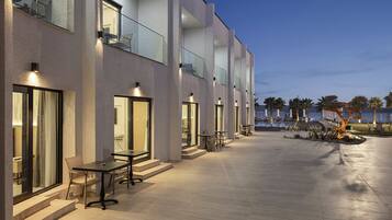 A modern hotel with outdoor seating, a pool, and a view of the ocean.