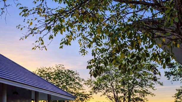 A building with a covered outdoor area, surrounded by trees and a clear sky. - Na Ville Resort (Ton Pho)